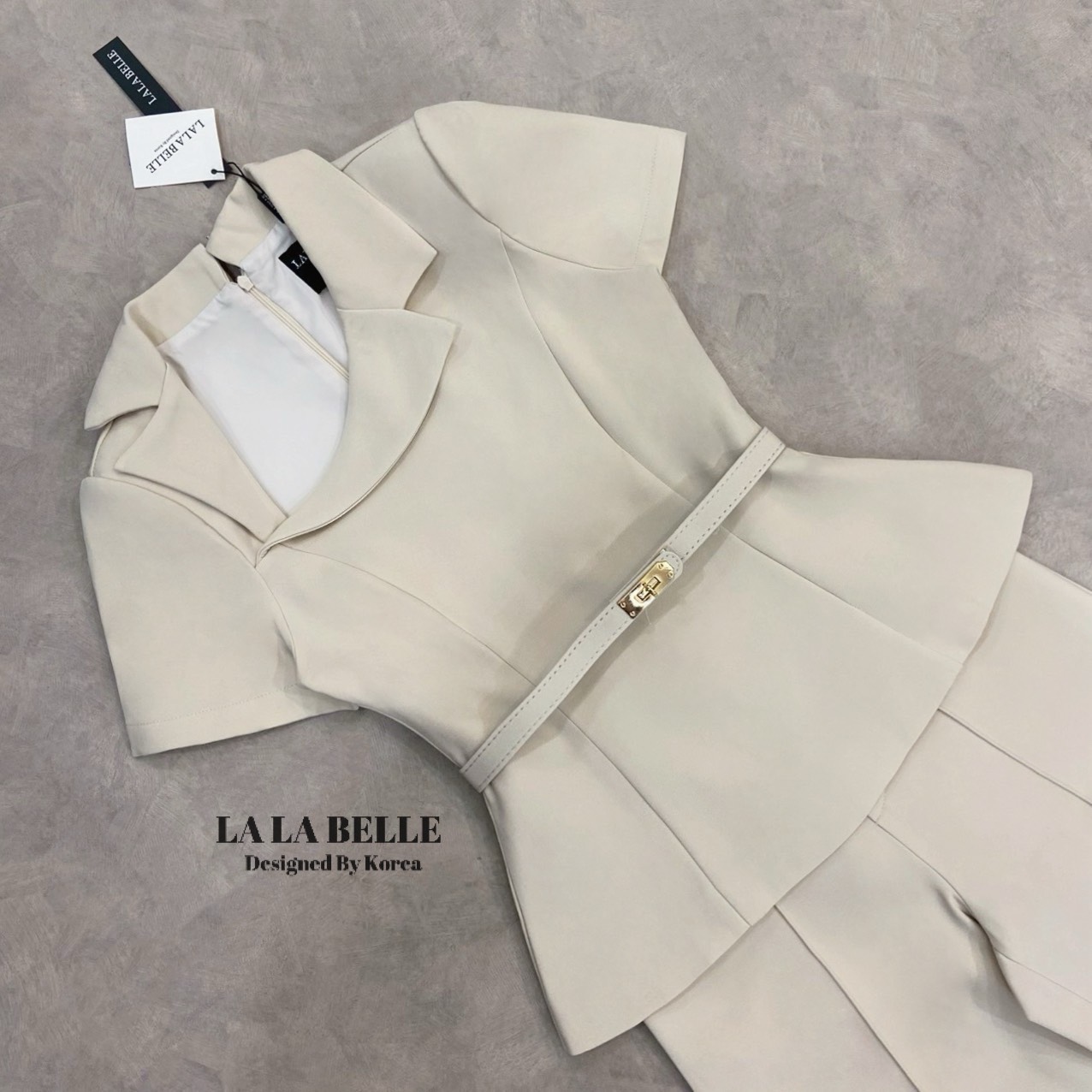 เซต3ชิ้นเสื้อผ้าสูทคอปกสูทเฉียงแขนสั้นเข้ารูปเข้าเอวชายทรงบานออกมาพร้อมกางเกงขายาวทรงกระบอกกลางตีเกล็ดหน้ายาวทำให้ดูผอมมีกระเป๋ากางเกงใส่เข้าชุดกับเข็มขัดสีเดียวกับชุดทั้งชุดเป็นผ้าสูทอัดกาวผ้ามีน้ำหนัก