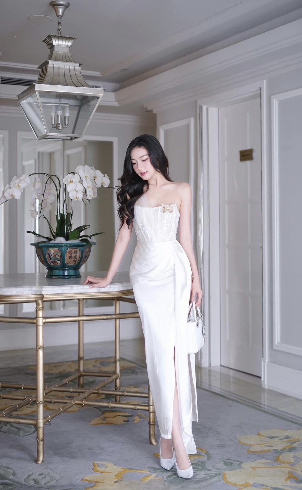 เดรสยาวสีขาวดีไซน์เก๋ อกเก็ตล็อคทรงเป็นผ้าลูกไม้ ( เสริมฟองน้ำและซิปหลังซ่อนอย่างดี ) เพิ่มความเก๋ด้วยแต่งผ้าชีฟองสีขาวพาดบ่าหนึ่งข้าง ช่วงกระโปรงทรงตรงยาวผ่าสูงถึงช่วงต้นขา แต่งผ้าอีกชั้นจับจีบไขว้ข้างและติดด้วยเข็มกลัดผีเสื้อสีทองปล่อยชายพริ้วลงมาสวยมาก