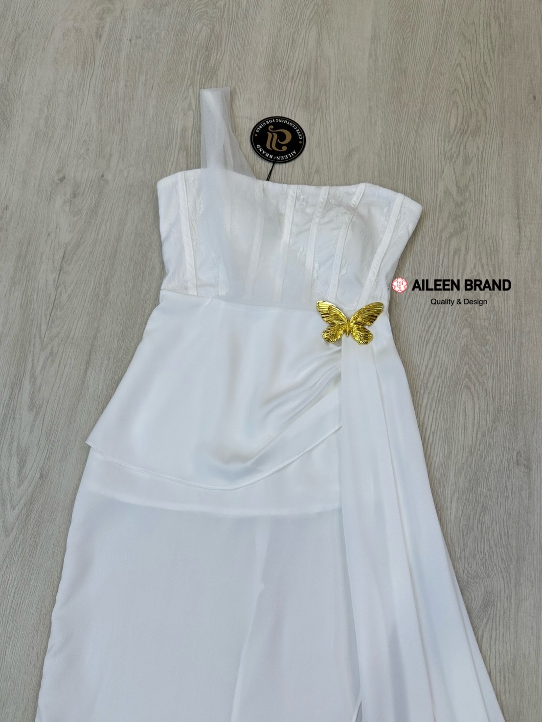 เดรสยาวสีขาวดีไซน์เก๋ อกเก็ตล็อคทรงเป็นผ้าลูกไม้ ( เสริมฟองน้ำและซิปหลังซ่อนอย่างดี ) เพิ่มความเก๋ด้วยแต่งผ้าชีฟองสีขาวพาดบ่าหนึ่งข้าง ช่วงกระโปรงทรงตรงยาวผ่าสูงถึงช่วงต้นขา แต่งผ้าอีกชั้นจับจีบไขว้ข้างและติดด้วยเข็มกลัดผีเสื้อสีทองปล่อยชายพริ้วลงมาสวยมาก