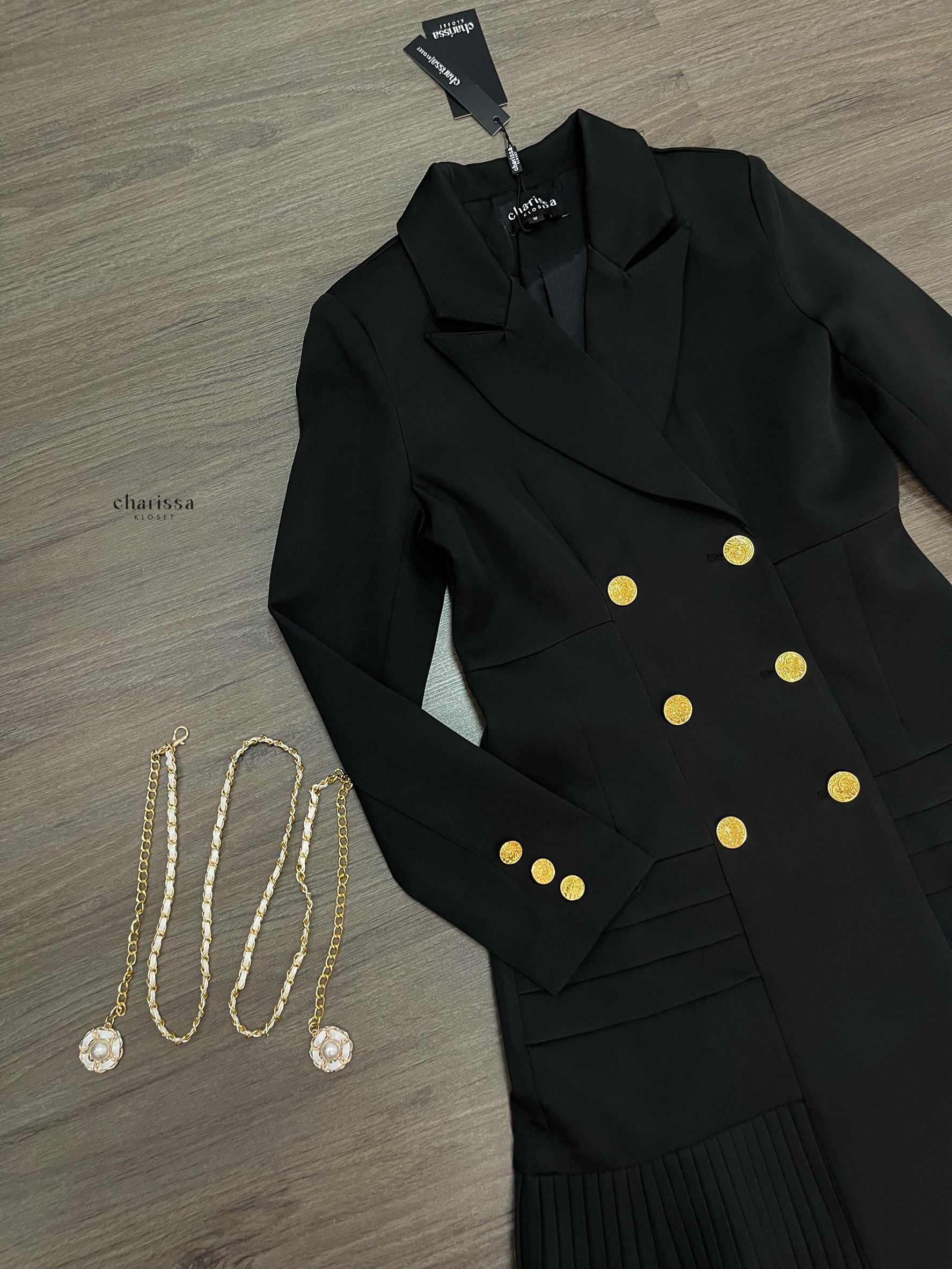 เดรสสูทกระดุมทองทรงหรู สไตล์มินิมอลคลาสสิกที่ออกแบบมาเพื่อเสริมความสง่างามทุกอิริยาบถ ตัวชุดเป็นทรง double-breasted เข้ารูปกำลังดี เน้นสัดส่วนช่วงเอวให้ดูเพรียว เรียบหรูแต่ทรงพลัง กระโปรงด้านล่างตัดต่อด้วย ดีเทลพลีท (Pleated Hem)