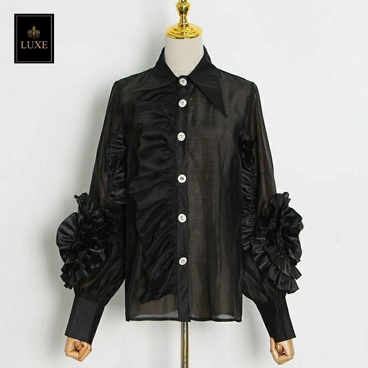 Label : LUXE เสื้อเชิ้ตคอปกแหลมแขนยาว ผ่าหน้าติดกระดุมเพชร สาบเสื้อแต่งระบาย ดีเทลแขนเสื้อแต่งด้วยผ้าในตัวเป็นรูปดอกไม้ ทำจากผ้าไหมเครปผสม เนื้อนุ่ม โปร่ง เบาสบายแต่ให้ความเป็นทรง