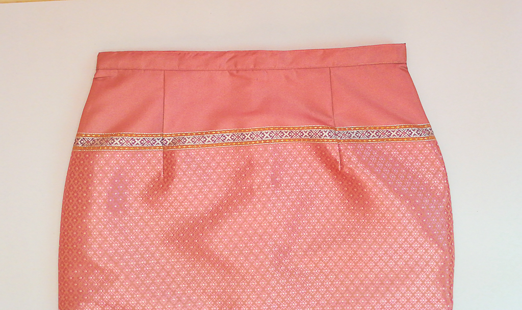 ผ้าถุงไหมสำเร็จรูป (สีชมพูอ่อน ลายสุโขทัย ทรงกระโปรง) งานตัดเย็บประณีต อัดผ้ากาวตามสีของผ้าถุง เนื้องานดีเกรด A (รอบเอว 30 นิ้ว)