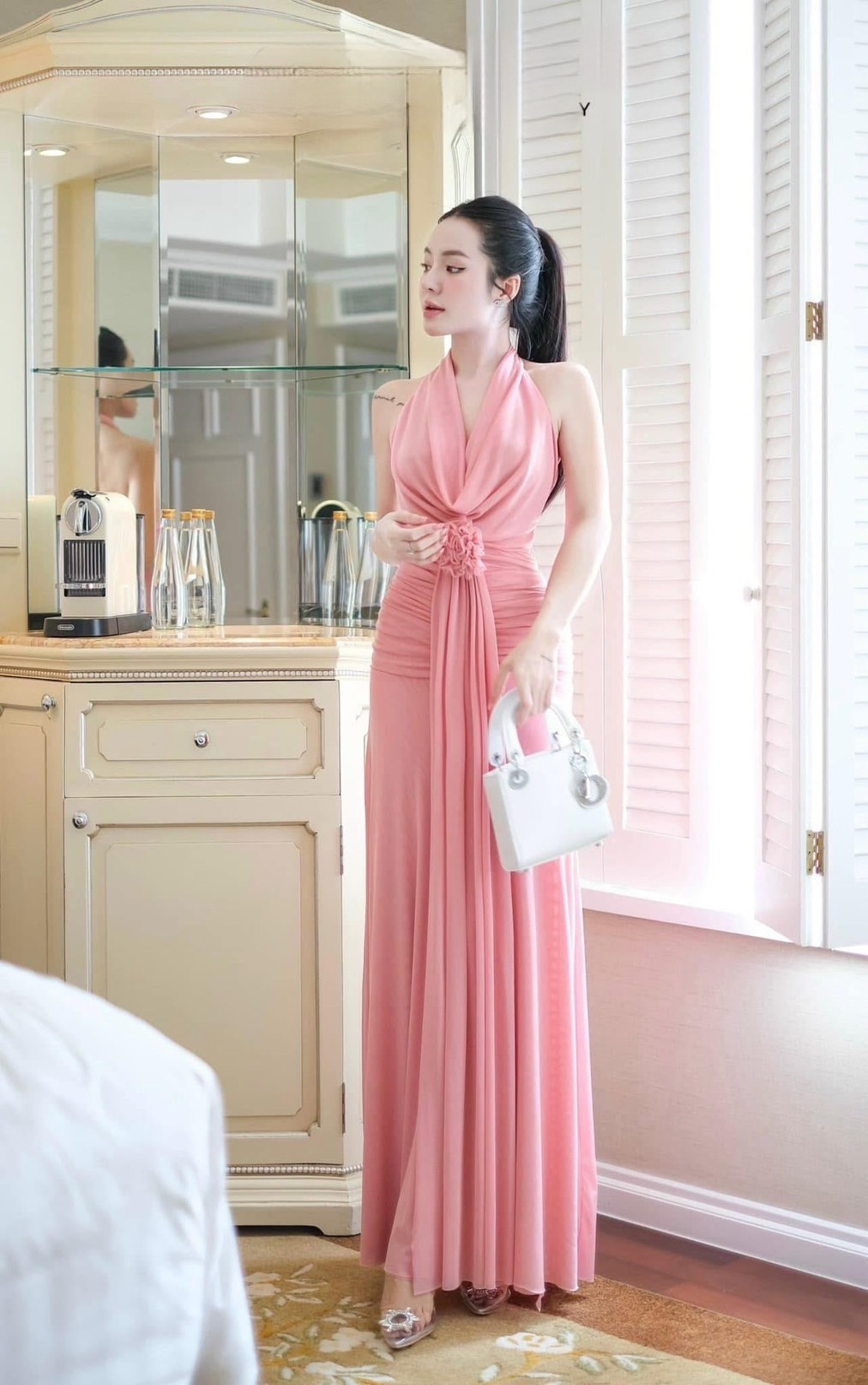 เดรสยาวสีชมพูดีไซน์แต่งผ้าคล้องคอแขนกุดโชว์ด้านหลังด้านหน้าช่วงอกคอวีจับผ้าย่นเข้าตรงกลาง ( ฟองน้ำซิปหลังซ่อนอย่างดี ) ตัวเดรสทรงเข้ารูปสวยช่วงกระโปรงทรงพริ้วจับจีบย่นด้านข้างช่วงสะโพก เพิ่มความเก๋ด้วยการแต่งอะไหล่ดอกไม้ช่วงเอวพร้อมกับผ้าพริ้วยาวเท่าตัวชุ