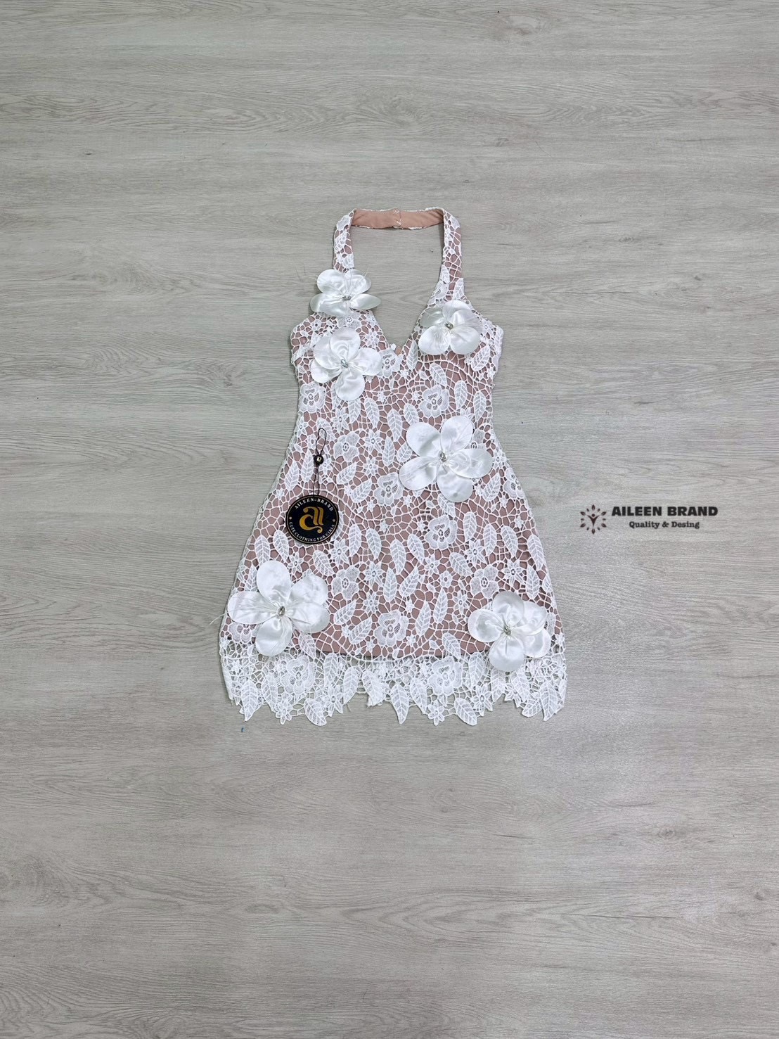 มินิเดรสคล้องคอ ช่วงอกเสริมฟองน้ำ งานเนื้อผ้าฉลุลูกไม้สีขาว ตัดกับชับในสีเนื้อ ดีเทลแต่งดอกไม้3D แซมด้วยขนนกและเพชร ด้านหน้า ปลายชายกระโปรงแต่งยั๊ก (ซิปหลัง)