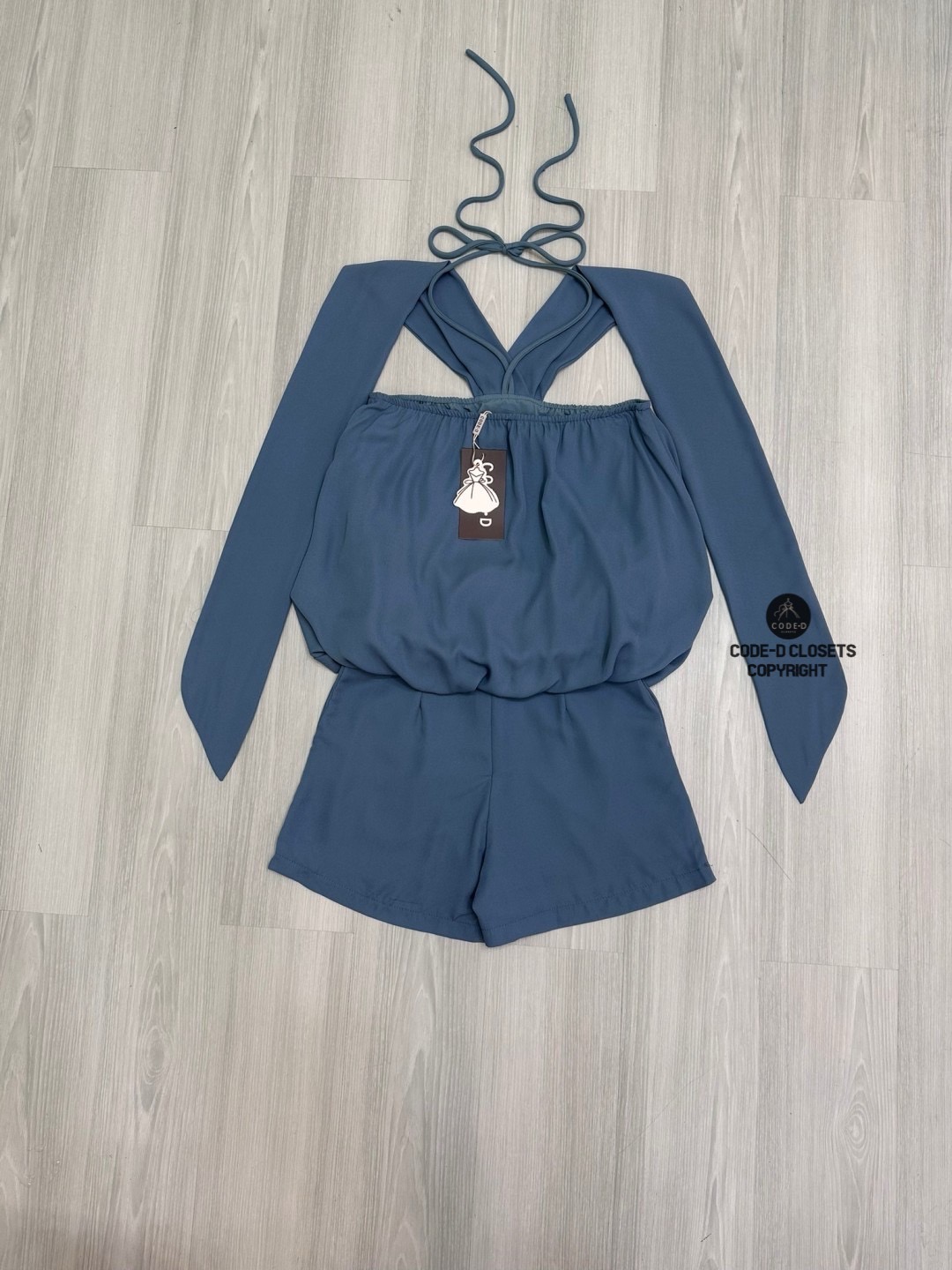 Set 2 ชิ้นสีครามผ้าชีฟองเนี้อทราย ตัวเสื้อแขนกุดสายคล้องคอผูกโบว์และสายคาดไหล่ระบาย อกแต่งอะไหล่เข็มกลัดดอกไม้ ตัวเสื้อจับจีบคลาย ๆ ทรงทวย ตัวเสื้อเป็นทรงฟักทอง (สม็อคจั้มเอว)ดีไซน์เว้าหลัง สวมใส่ง่าย มาพร้อมกับกางเกงขาสั้น (ซิปหลัง) เนื้อผ้าชีฟองนี้ทรายอ