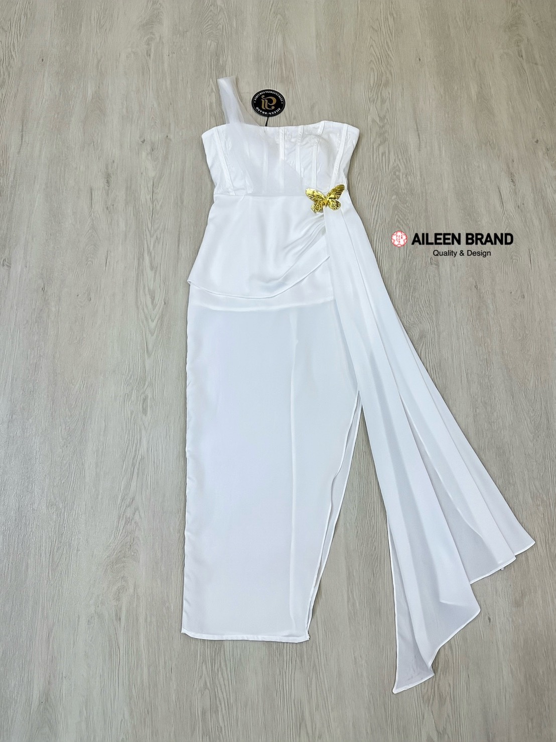 เดรสยาวสีขาวดีไซน์เก๋ อกเก็ตล็อคทรงเป็นผ้าลูกไม้ ( เสริมฟองน้ำและซิปหลังซ่อนอย่างดี ) เพิ่มความเก๋ด้วยแต่งผ้าชีฟองสีขาวพาดบ่าหนึ่งข้าง ช่วงกระโปรงทรงตรงยาวผ่าสูงถึงช่วงต้นขา แต่งผ้าอีกชั้นจับจีบไขว้ข้างและติดด้วยเข็มกลัดผีเสื้อสีทองปล่อยชายพริ้วลงมาสวยมาก