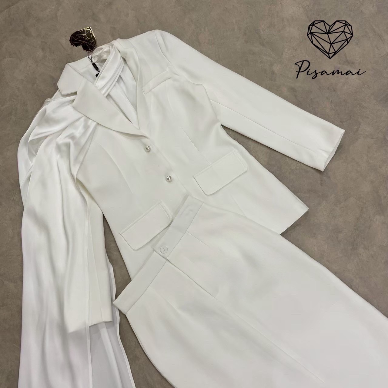 เซ็ตเสื้อสูทเบเซอร์สีขาวแขนยาว มีกิมมิคช่วงคอเป็นผ้าพาดหางปลายาว มาคู่กับกระโปรงทรงสอบสีขาว ทรงสวย หรู ดูแพง ใส่ไปงานแต่งแบบเฟียสๆ แกรมๆ ได้ไม่ซ้ำใคร