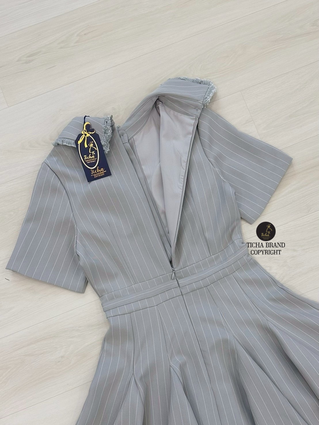 เดรสสั้นคอปกสีเทาลายทาง ดีเทลแต่งไหมพรมตรงปกเสื้อและชายกระโปรง แต่งอ่ะไหล่กระดุม และอ่ะไหล่สีเงินตรงช่วงเอวของชุด กระโปรงจับจีบบานออกรอบตัว (อกเสริมฟองน้ำ