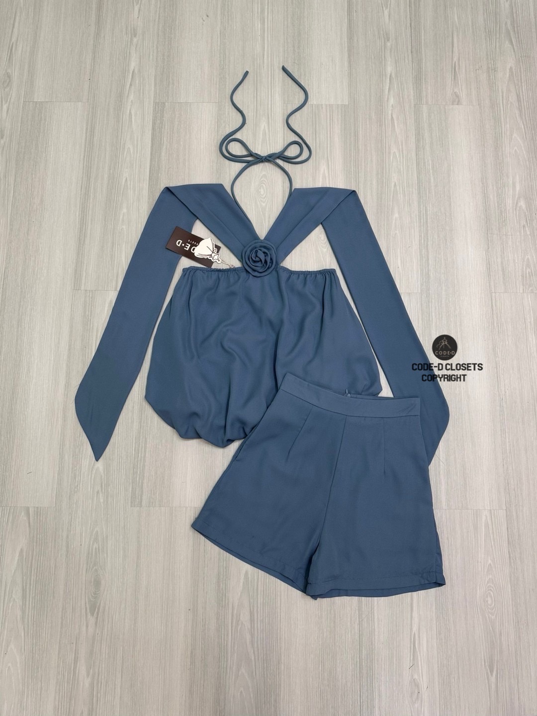 Set 2 ชิ้นสีครามผ้าชีฟองเนี้อทราย ตัวเสื้อแขนกุดสายคล้องคอผูกโบว์และสายคาดไหล่ระบาย อกแต่งอะไหล่เข็มกลัดดอกไม้ ตัวเสื้อจับจีบคลาย ๆ ทรงทวย ตัวเสื้อเป็นทรงฟักทอง (สม็อคจั้มเอว)ดีไซน์เว้าหลัง สวมใส่ง่าย มาพร้อมกับกางเกงขาสั้น (ซิปหลัง) เนื้อผ้าชีฟองนี้ทรายอ