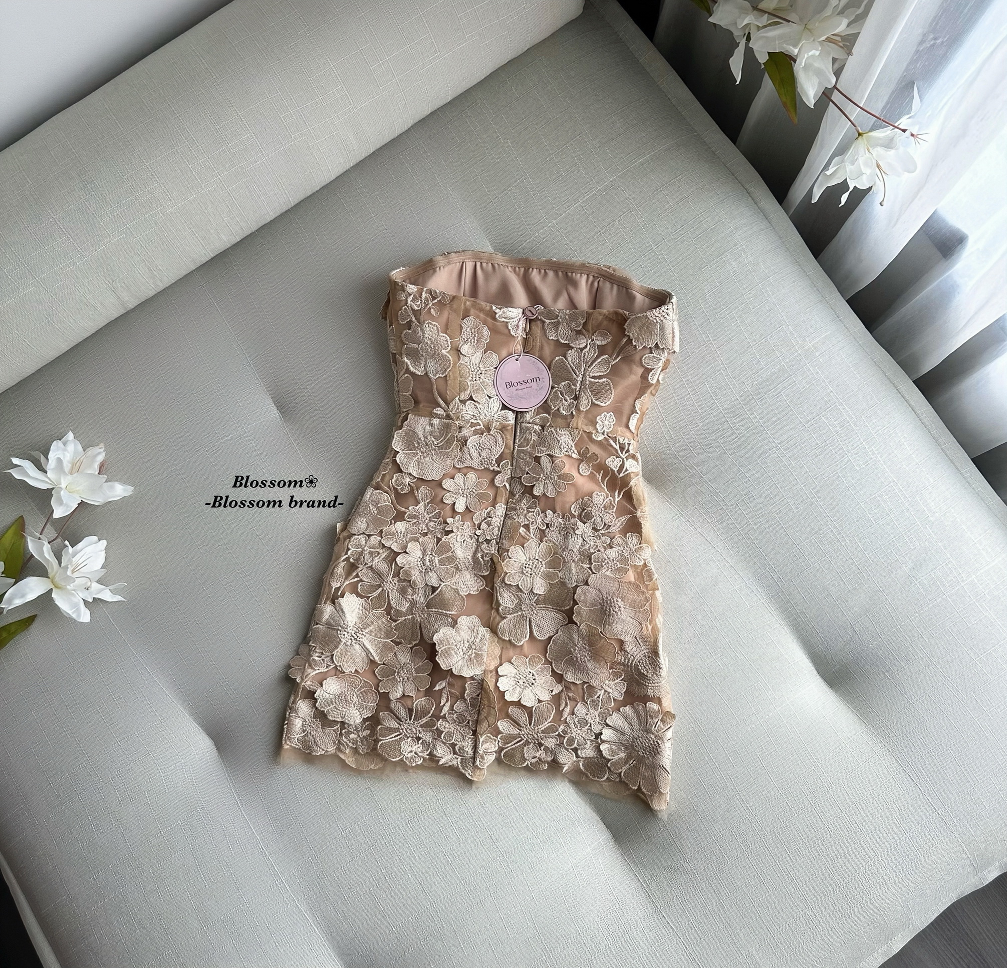 เดรสสั้นเกาะอก ออกแบบในสไตล์หรูหราเฉพาะตัว โดดเด่นด้วยงาน ปักลายดอกไม้และลูกไม้ 3 มิติ ทั้งตัว ให้เลเยอร์สวยเด่นแบบงานพรีเมียม ใส่แล้วช่วยขับผิวและทำให้ลุคดูแพง ช่วงหน้าอกมีฟองน้ำในตัว