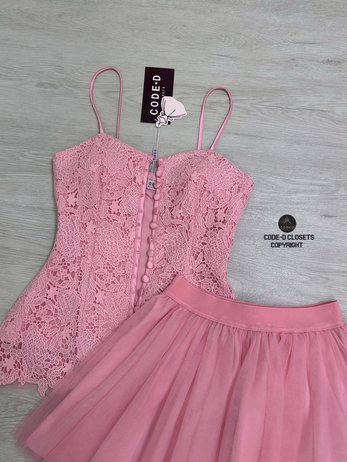 เซต2ชิ้น เสื้อสายเดี่ยวกระดุมหน้าเรียงยาว อกเสริมฟองน้ำ ปลายชายเสื้อแต่งบานออกเล็กน้อย งานเนื้อผ้าลูกไม้สีชมพู แน่นๆ มีชับในอย่างดี แมทซ์กับกระโปรงสั้น แต่งผ้ามุ้งตะข่ายด้านนอก มีชับใน เอวสม็อค