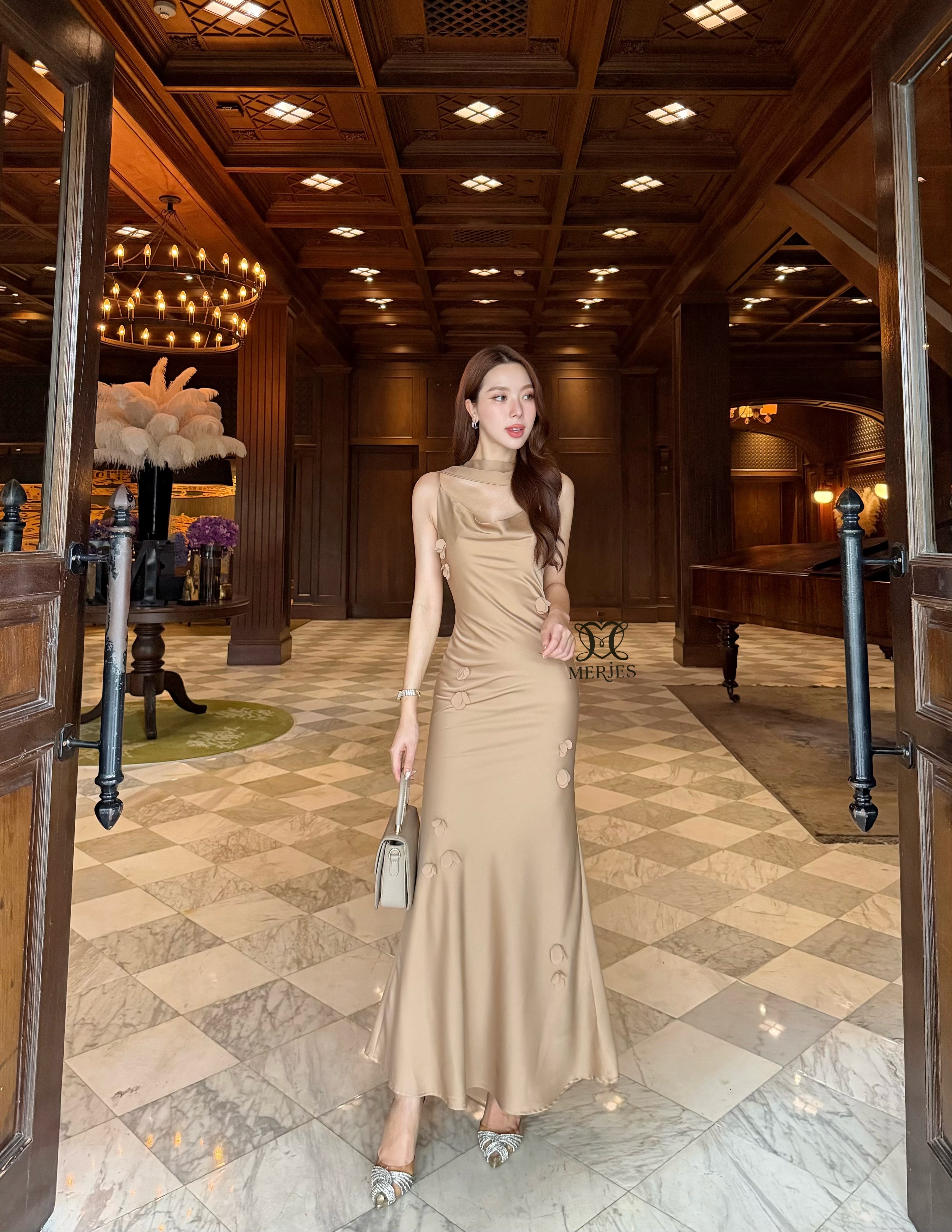 𝐌𝐄𝐑𝐉𝐄𝐒 𝐒𝐓𝐔𝐃𝐈𝐎 (เมอร์เจส) 𝐃𝐞𝐭𝐚𝐢𝐥 : เดรสยาวสีน้ำตาลทองผ้าซาตินสายเดี่ยวเข้ารูปสายสามารถปรับได้แต่งดีเทลด้วยดอกไม้