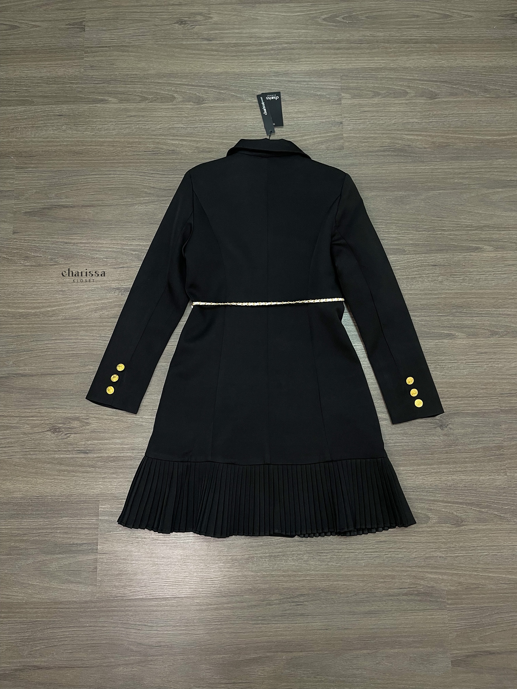 เดรสสูทกระดุมทองทรงหรู สไตล์มินิมอลคลาสสิกที่ออกแบบมาเพื่อเสริมความสง่างามทุกอิริยาบถ ตัวชุดเป็นทรง double-breasted เข้ารูปกำลังดี เน้นสัดส่วนช่วงเอวให้ดูเพรียว เรียบหรูแต่ทรงพลัง กระโปรงด้านล่างตัดต่อด้วย ดีเทลพลีท (Pleated Hem)