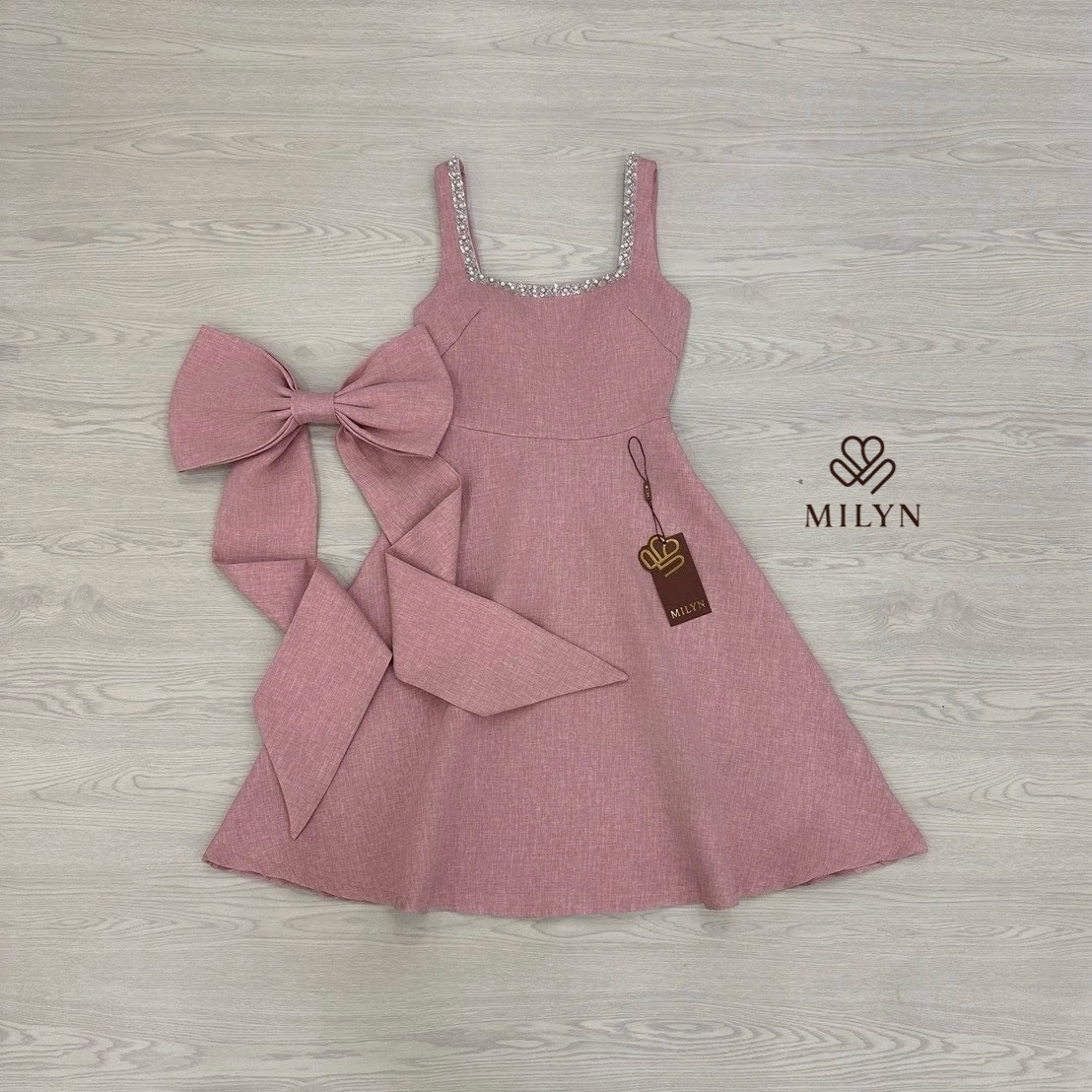 เดรสสีชมพูตัวเดรสแขนกุดแต่งอะไหล่เพชรขอบชุดช่วงอกเชื่อมไปด้านหลัง ( เดรสเสริมฟองน้ำและซิปหลังซ่อนอย่างดี ) และมีอะไหล่โบว์ใหญ่ริบบิ้นยาวให้อีกชิ้นมีกเข็มกลัดสามารถติดตรงด้านหลังได้ หรือถอดออกได้ ตัวกระโปรงทรงพลิ้วสวย เนื้อผ้าหนามีเทคเจอร์และมีซับในทั้งตัว