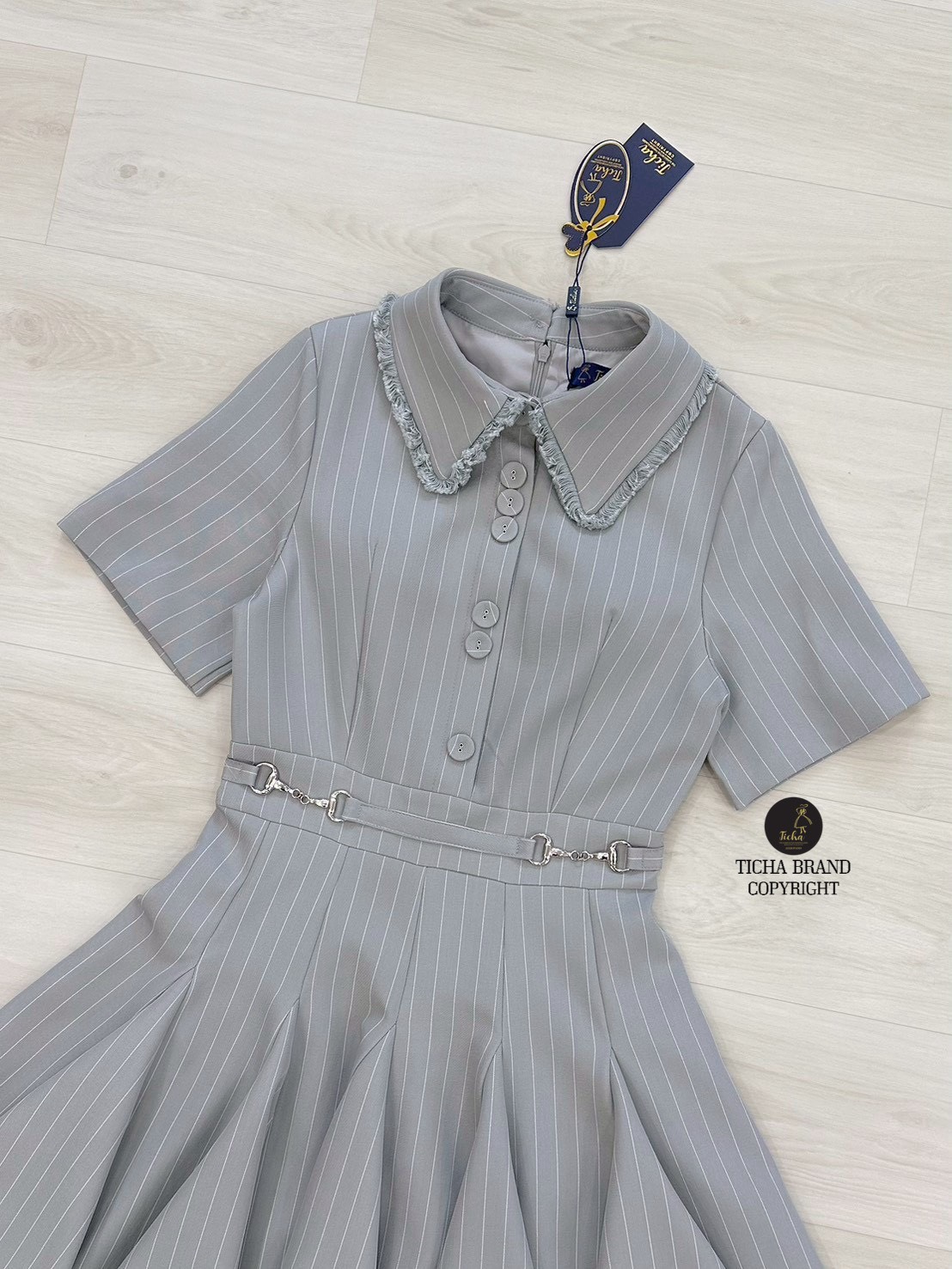 เดรสสั้นคอปกสีเทาลายทาง ดีเทลแต่งไหมพรมตรงปกเสื้อและชายกระโปรง แต่งอ่ะไหล่กระดุม และอ่ะไหล่สีเงินตรงช่วงเอวของชุด กระโปรงจับจีบบานออกรอบตัว (อกเสริมฟองน้ำ