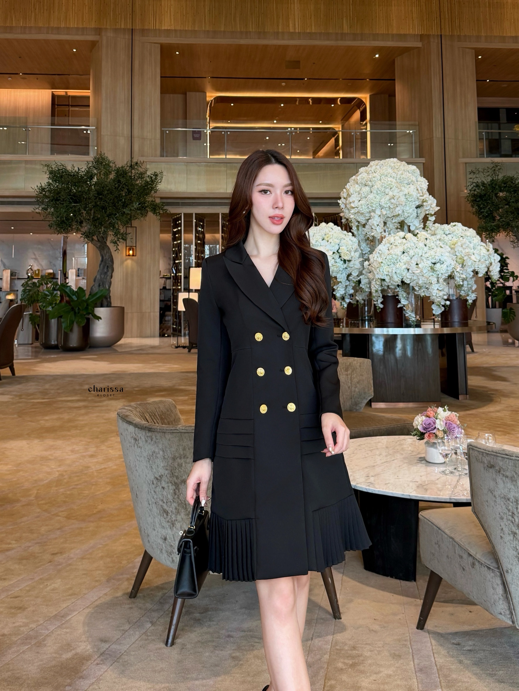 เดรสสูทกระดุมทองทรงหรู สไตล์มินิมอลคลาสสิกที่ออกแบบมาเพื่อเสริมความสง่างามทุกอิริยาบถ ตัวชุดเป็นทรง double-breasted เข้ารูปกำลังดี เน้นสัดส่วนช่วงเอวให้ดูเพรียว เรียบหรูแต่ทรงพลัง กระโปรงด้านล่างตัดต่อด้วย ดีเทลพลีท (Pleated Hem)