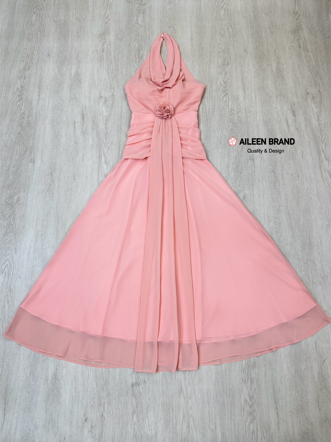 เดรสยาวสีชมพูดีไซน์แต่งผ้าคล้องคอแขนกุดโชว์ด้านหลังด้านหน้าช่วงอกคอวีจับผ้าย่นเข้าตรงกลาง ( ฟองน้ำซิปหลังซ่อนอย่างดี ) ตัวเดรสทรงเข้ารูปสวยช่วงกระโปรงทรงพริ้วจับจีบย่นด้านข้างช่วงสะโพก เพิ่มความเก๋ด้วยการแต่งอะไหล่ดอกไม้ช่วงเอวพร้อมกับผ้าพริ้วยาวเท่าตัวชุ