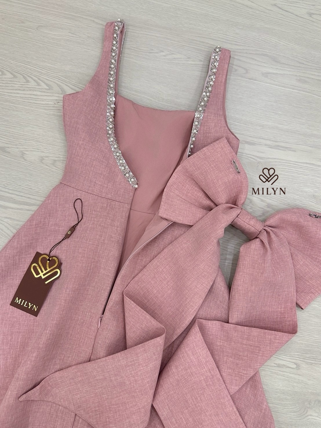 เดรสสีชมพูตัวเดรสแขนกุดแต่งอะไหล่เพชรขอบชุดช่วงอกเชื่อมไปด้านหลัง ( เดรสเสริมฟองน้ำและซิปหลังซ่อนอย่างดี ) และมีอะไหล่โบว์ใหญ่ริบบิ้นยาวให้อีกชิ้นมีกเข็มกลัดสามารถติดตรงด้านหลังได้ หรือถอดออกได้ ตัวกระโปรงทรงพลิ้วสวย เนื้อผ้าหนามีเทคเจอร์และมีซับในทั้งตัว