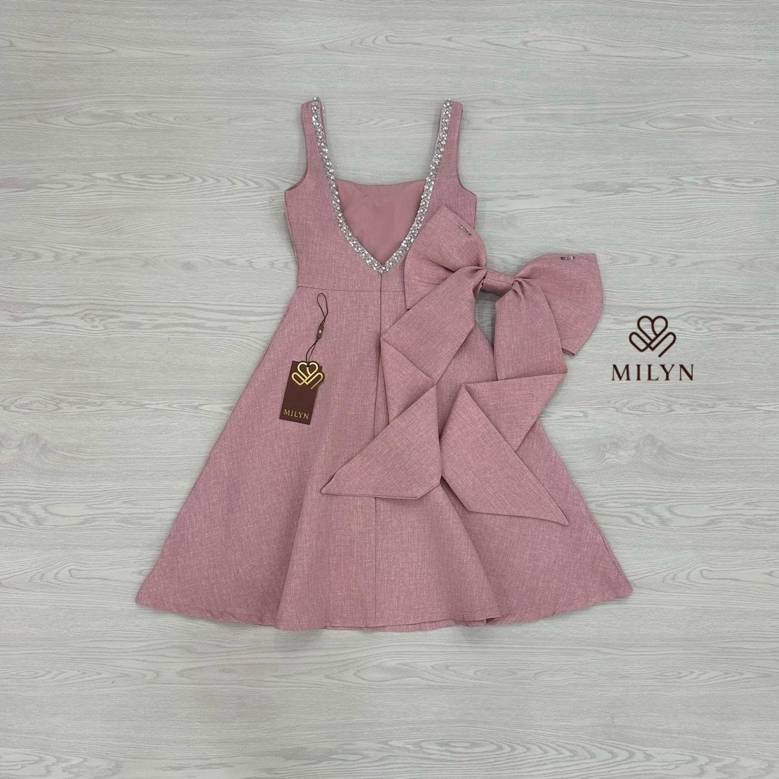 เดรสสีชมพูตัวเดรสแขนกุดแต่งอะไหล่เพชรขอบชุดช่วงอกเชื่อมไปด้านหลัง ( เดรสเสริมฟองน้ำและซิปหลังซ่อนอย่างดี ) และมีอะไหล่โบว์ใหญ่ริบบิ้นยาวให้อีกชิ้นมีกเข็มกลัดสามารถติดตรงด้านหลังได้ หรือถอดออกได้ ตัวกระโปรงทรงพลิ้วสวย เนื้อผ้าหนามีเทคเจอร์และมีซับในทั้งตัว