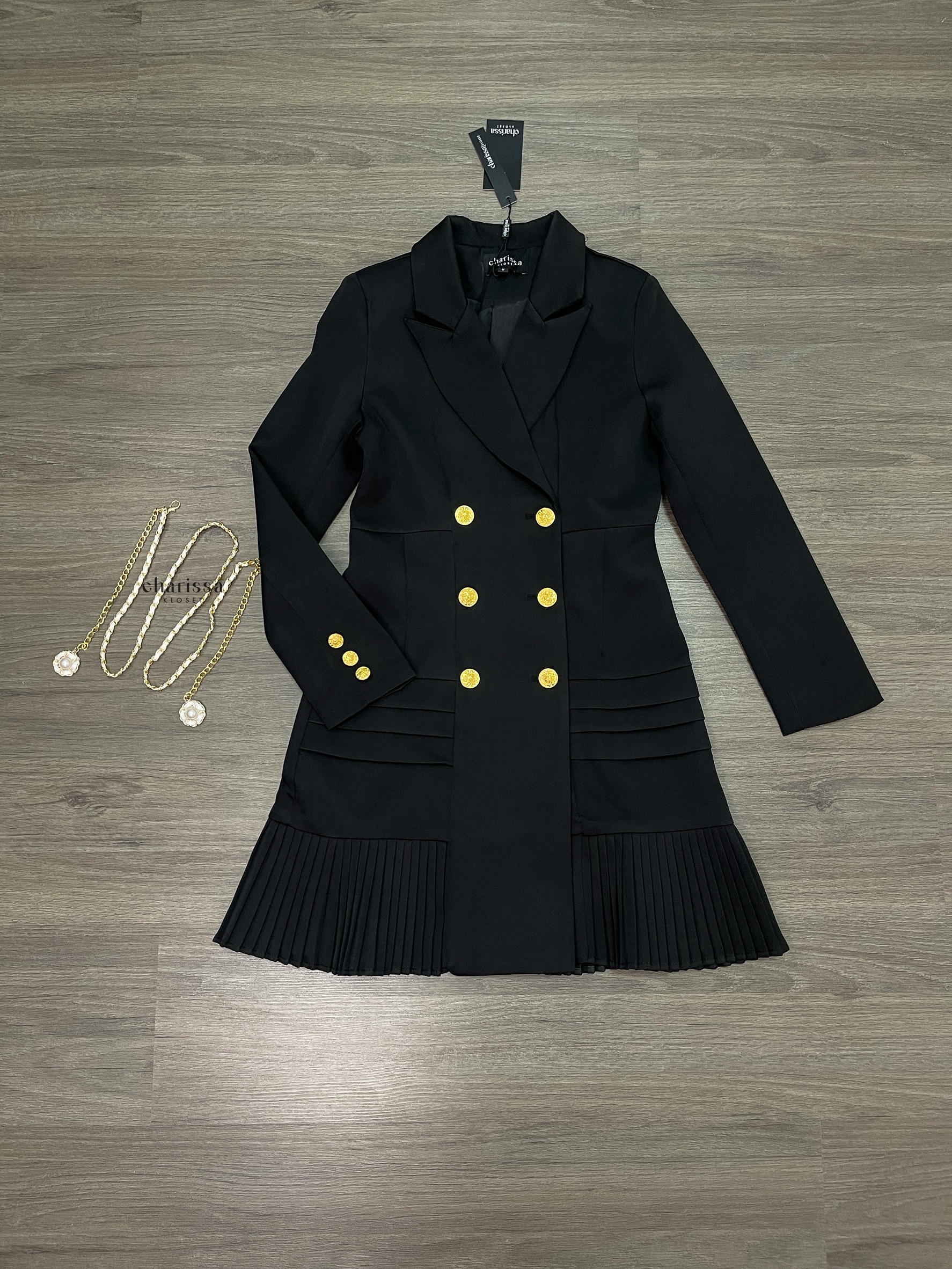 เดรสสูทกระดุมทองทรงหรู สไตล์มินิมอลคลาสสิกที่ออกแบบมาเพื่อเสริมความสง่างามทุกอิริยาบถ ตัวชุดเป็นทรง double-breasted เข้ารูปกำลังดี เน้นสัดส่วนช่วงเอวให้ดูเพรียว เรียบหรูแต่ทรงพลัง กระโปรงด้านล่างตัดต่อด้วย ดีเทลพลีท (Pleated Hem)