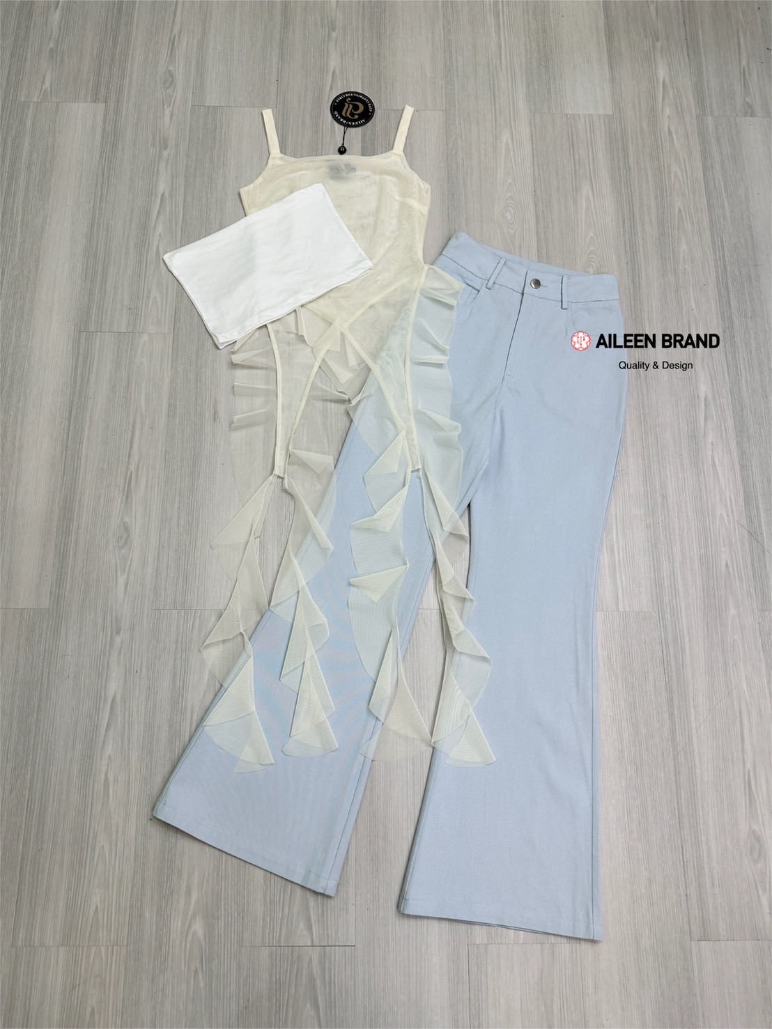 Set 2 ชิ้น เสื้อสายเดี่ยวเนื้อผ้าซีทรูอกเหลี่ยมแขนกุดทรงพอดีตัว ( ไม่เสริมฟองน้ำไม่มีซิปหลัง ) ชายแต่งปล่อยชายเฉียงเป็นระบายทั้งด้านหน้าและด้านหลัง มีเกาะอกสีขาวซับในแยกชิ้นให้อีกชิ้น มาพร้อมกับกางเกงขายาวเอวสูงสีฟ้าอมเทากระดุมและซิปด้านหน้า มีกระเป๋าล้วง