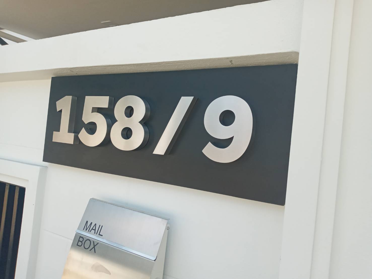 งานติดตั้งป้ายบ้านเลขที่ ตัวเลขสแตนเลสเนื้อเงินผิวแฮร์ไลน์ ยกขอบ 2cm. กันหลัง