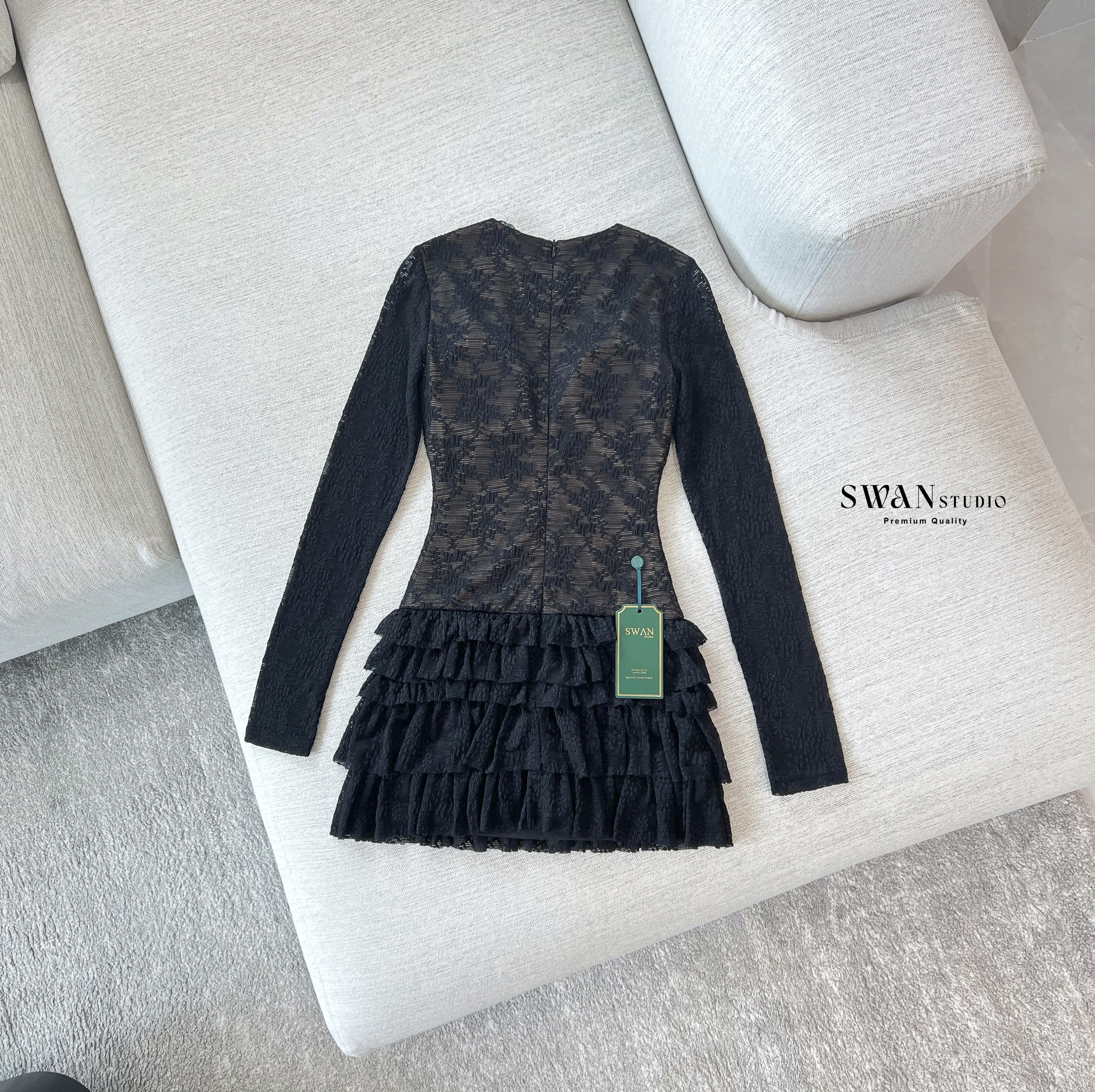 เดรสลูกไม้สีดำแขนยาวซีทรูซ้อนซับสีเนื้อ ดีไซน์เข้ารูปช่วงตัวคอวีลึกแต่งเข็มกลัดสีทองช่วงอกเพิ่มความหรูหราตัดต่อกระโปรงสั้นบานระบายเลเยอร์ชั้นๆด้วยผ้าลูกไม้ดูพริ้วหวานแฝงความเซ็กซี่ลงตัวเหมาะกับลุคดินเนอร์หรือออกงานกลางคืนที่ต้องการความโดดเด่นและดูแพง