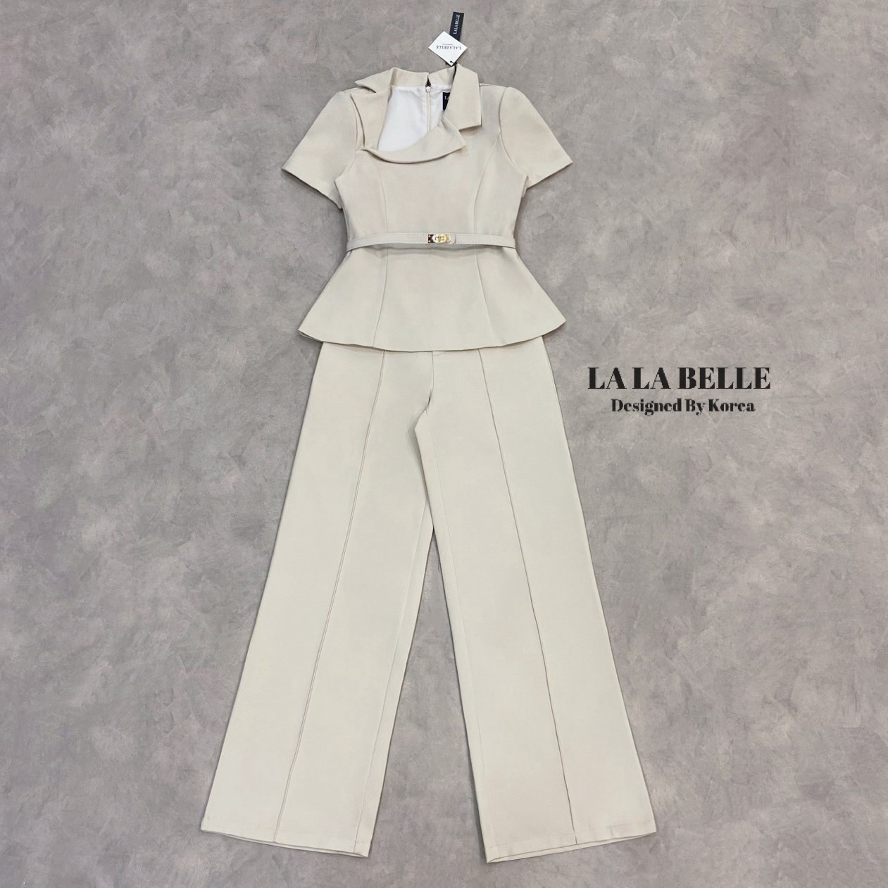 เซต3ชิ้นเสื้อผ้าสูทคอปกสูทเฉียงแขนสั้นเข้ารูปเข้าเอวชายทรงบานออกมาพร้อมกางเกงขายาวทรงกระบอกกลางตีเกล็ดหน้ายาวทำให้ดูผอมมีกระเป๋ากางเกงใส่เข้าชุดกับเข็มขัดสีเดียวกับชุดทั้งชุดเป็นผ้าสูทอัดกาวผ้ามีน้ำหนัก