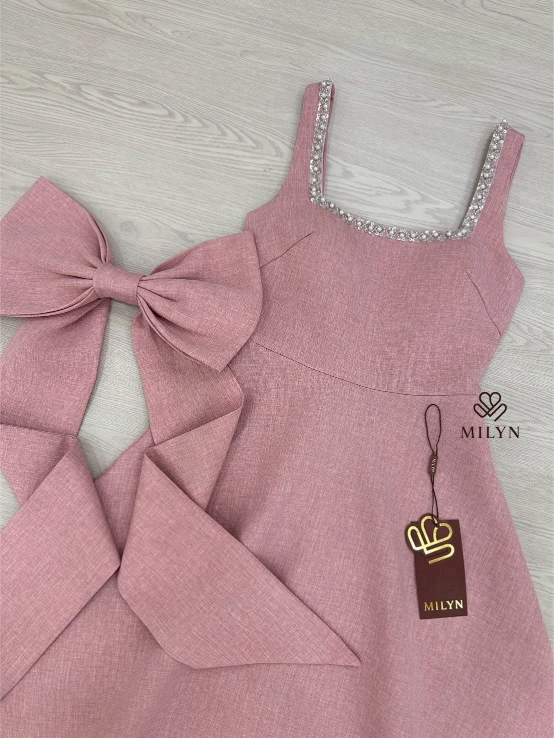 เดรสสีชมพูตัวเดรสแขนกุดแต่งอะไหล่เพชรขอบชุดช่วงอกเชื่อมไปด้านหลัง ( เดรสเสริมฟองน้ำและซิปหลังซ่อนอย่างดี ) และมีอะไหล่โบว์ใหญ่ริบบิ้นยาวให้อีกชิ้นมีกเข็มกลัดสามารถติดตรงด้านหลังได้ หรือถอดออกได้ ตัวกระโปรงทรงพลิ้วสวย เนื้อผ้าหนามีเทคเจอร์และมีซับในทั้งตัว