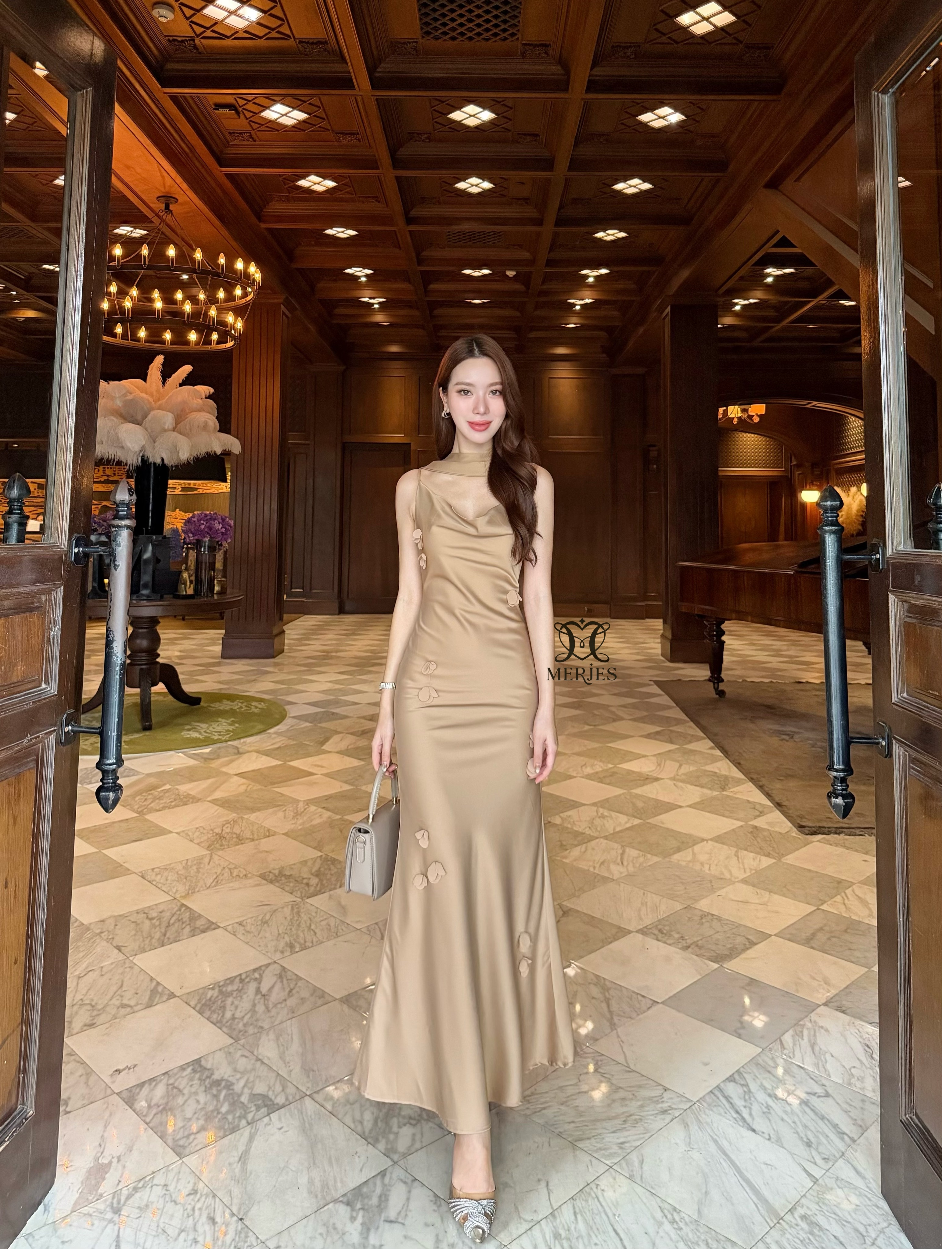 𝐌𝐄𝐑𝐉𝐄𝐒 𝐒𝐓𝐔𝐃𝐈𝐎 (เมอร์เจส) 𝐃𝐞𝐭𝐚𝐢𝐥 : เดรสยาวสีน้ำตาลทองผ้าซาตินสายเดี่ยวเข้ารูปสายสามารถปรับได้แต่งดีเทลด้วยดอกไม้