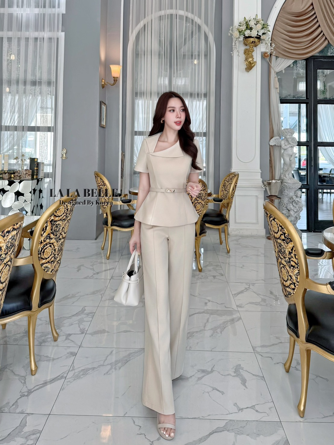 เซต3ชิ้นเสื้อผ้าสูทคอปกสูทเฉียงแขนสั้นเข้ารูปเข้าเอวชายทรงบานออกมาพร้อมกางเกงขายาวทรงกระบอกกลางตีเกล็ดหน้ายาวทำให้ดูผอมมีกระเป๋ากางเกงใส่เข้าชุดกับเข็มขัดสีเดียวกับชุดทั้งชุดเป็นผ้าสูทอัดกาวผ้ามีน้ำหนัก