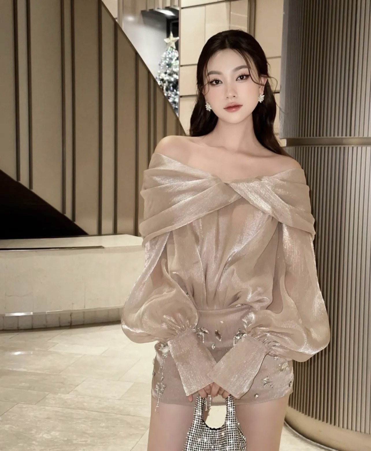 เดรสแขนยาวผ้าเนื้อเงาระยับ สีสวยมากก ดีไซน์ปาดไหล่เผยช่วงคอและไหล่สวย ด้านบนทรงโคร่งพลิ้วไหว ช่วงกระโปรงทรงเข้ารูปปักเพชรและคริสตัลหลากขนาดเพิ่มมิติและความหรูหรา เหมาะสำหรับลุคสวยแพงโดดเด่นทุกงาน