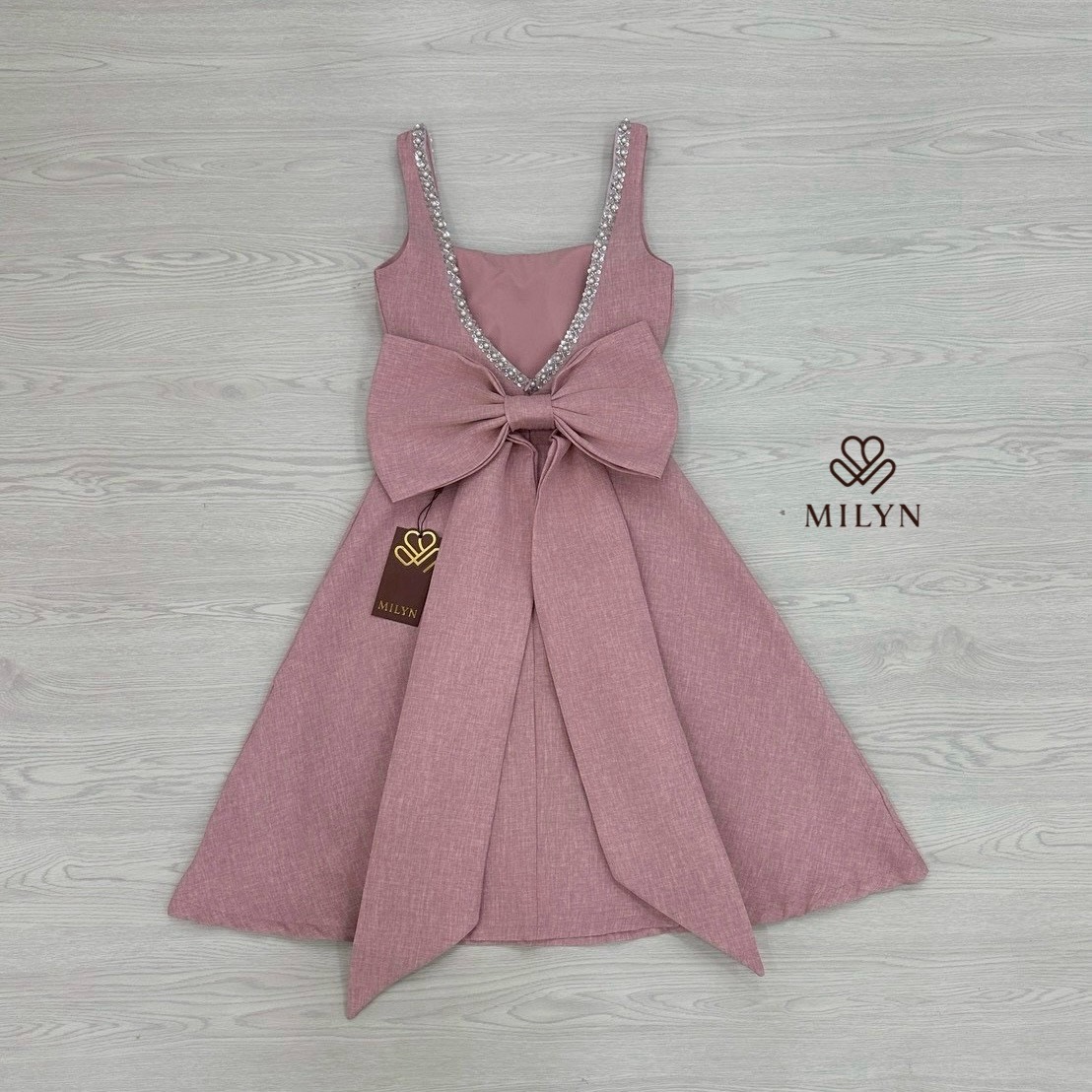 เดรสสีชมพูตัวเดรสแขนกุดแต่งอะไหล่เพชรขอบชุดช่วงอกเชื่อมไปด้านหลัง ( เดรสเสริมฟองน้ำและซิปหลังซ่อนอย่างดี ) และมีอะไหล่โบว์ใหญ่ริบบิ้นยาวให้อีกชิ้นมีกเข็มกลัดสามารถติดตรงด้านหลังได้ หรือถอดออกได้ ตัวกระโปรงทรงพลิ้วสวย เนื้อผ้าหนามีเทคเจอร์และมีซับในทั้งตัว