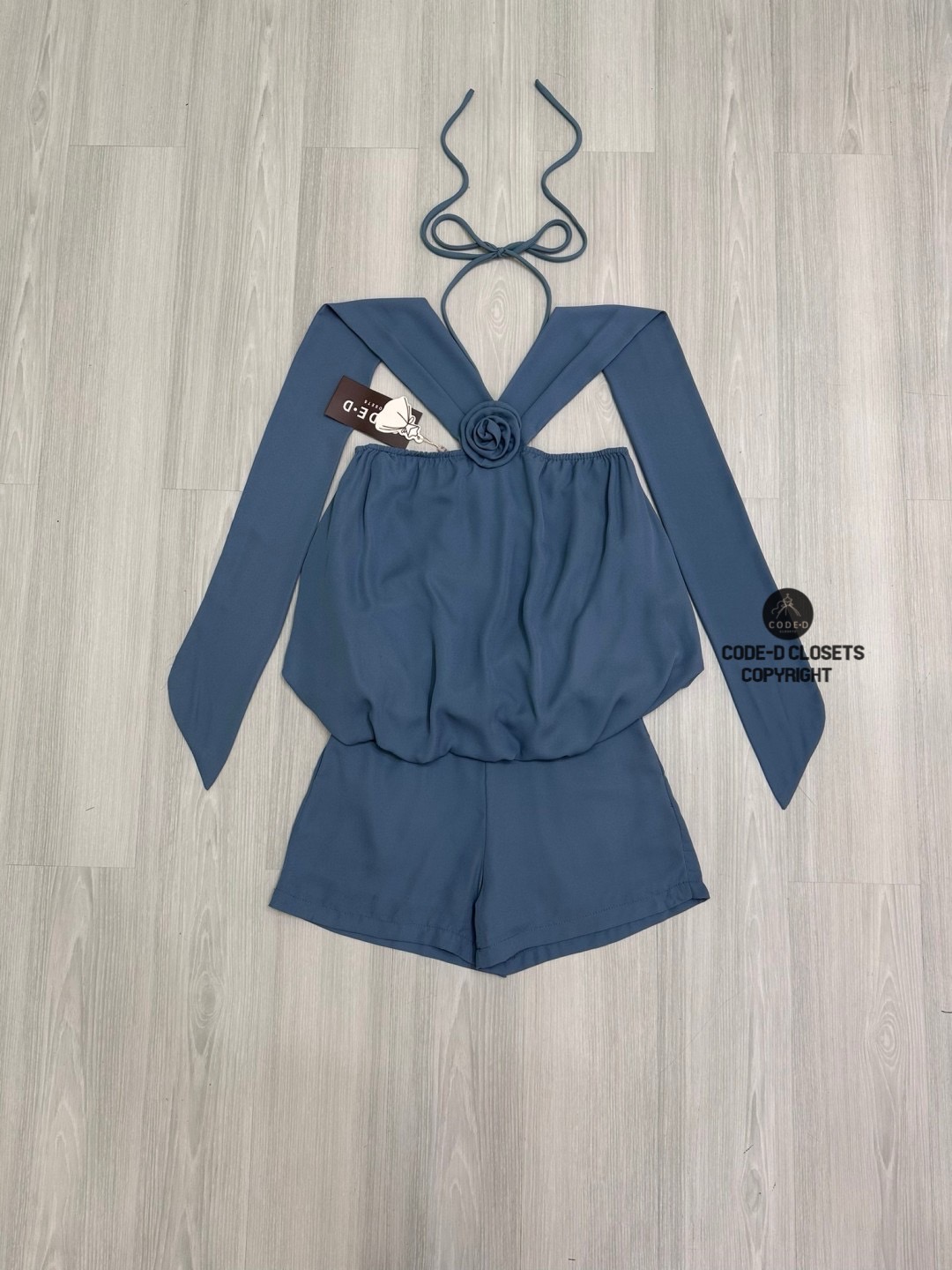 Set 2 ชิ้นสีครามผ้าชีฟองเนี้อทราย ตัวเสื้อแขนกุดสายคล้องคอผูกโบว์และสายคาดไหล่ระบาย อกแต่งอะไหล่เข็มกลัดดอกไม้ ตัวเสื้อจับจีบคลาย ๆ ทรงทวย ตัวเสื้อเป็นทรงฟักทอง (สม็อคจั้มเอว)ดีไซน์เว้าหลัง สวมใส่ง่าย มาพร้อมกับกางเกงขาสั้น (ซิปหลัง) เนื้อผ้าชีฟองนี้ทรายอ
