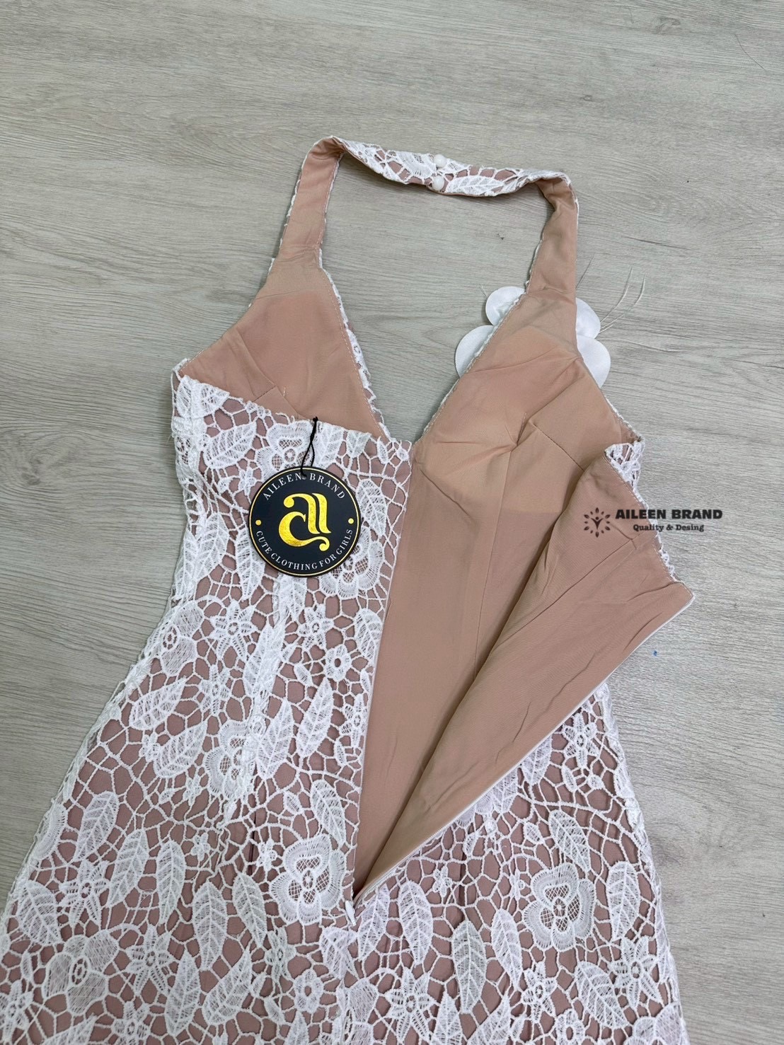 มินิเดรสคล้องคอ ช่วงอกเสริมฟองน้ำ งานเนื้อผ้าฉลุลูกไม้สีขาว ตัดกับชับในสีเนื้อ ดีเทลแต่งดอกไม้3D แซมด้วยขนนกและเพชร ด้านหน้า ปลายชายกระโปรงแต่งยั๊ก (ซิปหลัง)