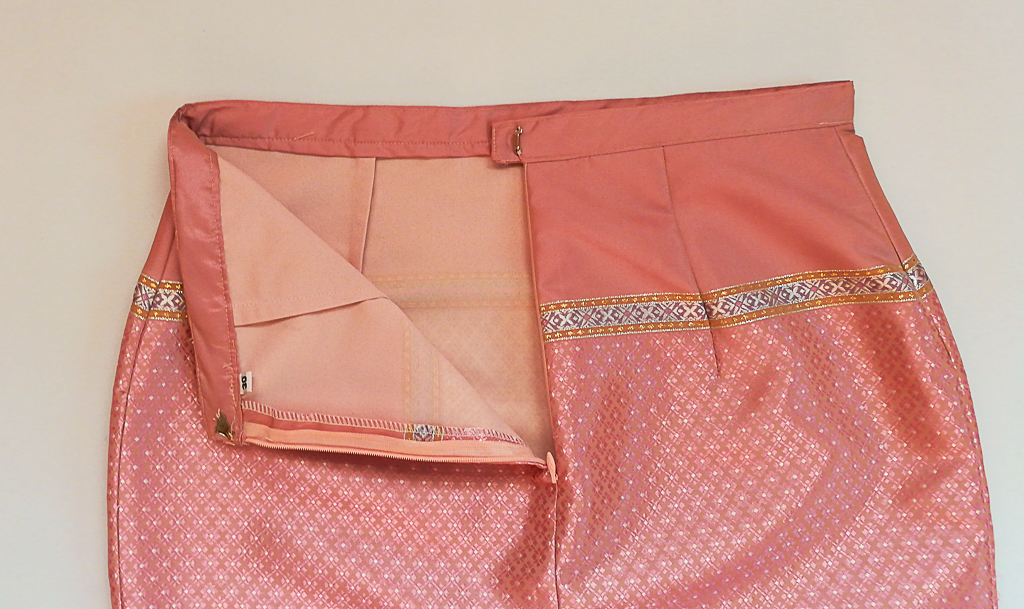 ผ้าถุงไหมสำเร็จรูป (สีชมพูอ่อน ลายสุโขทัย ทรงกระโปรง) งานตัดเย็บประณีต อัดผ้ากาวตามสีของผ้าถุง เนื้องานดีเกรด A (รอบเอว 30 นิ้ว)